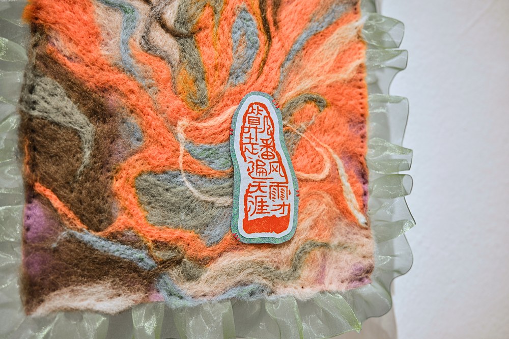 Close-up of orange and green felt piece with seal