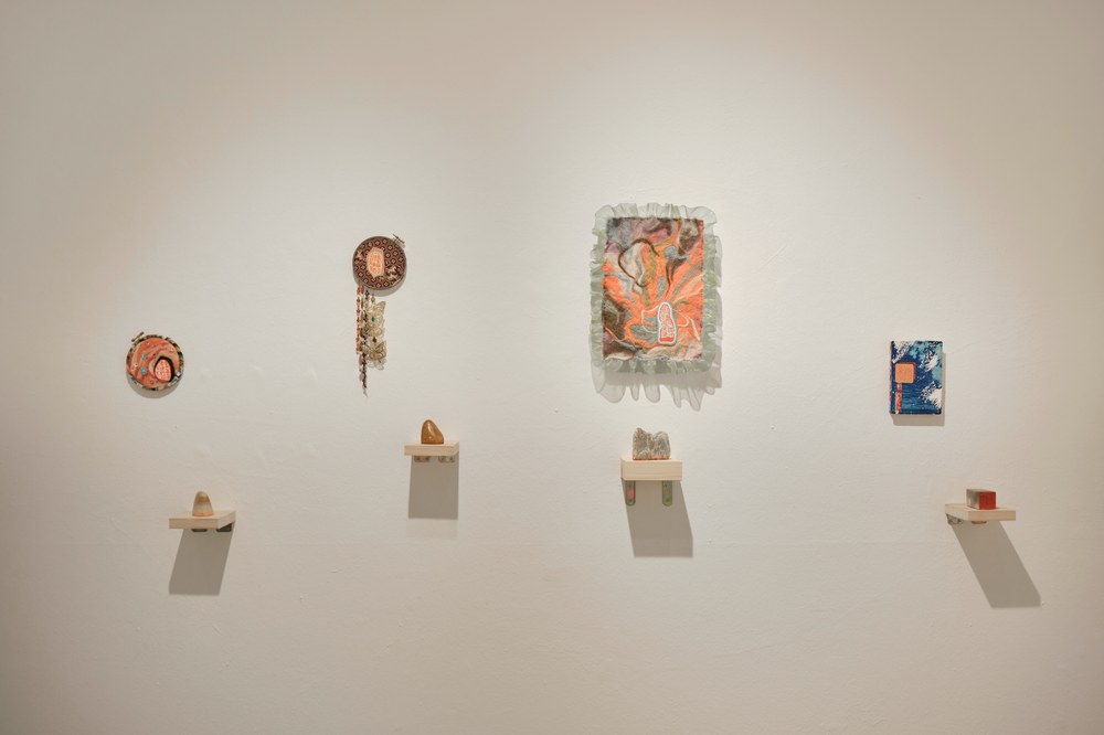 Wide view of exhibition wall showing four works