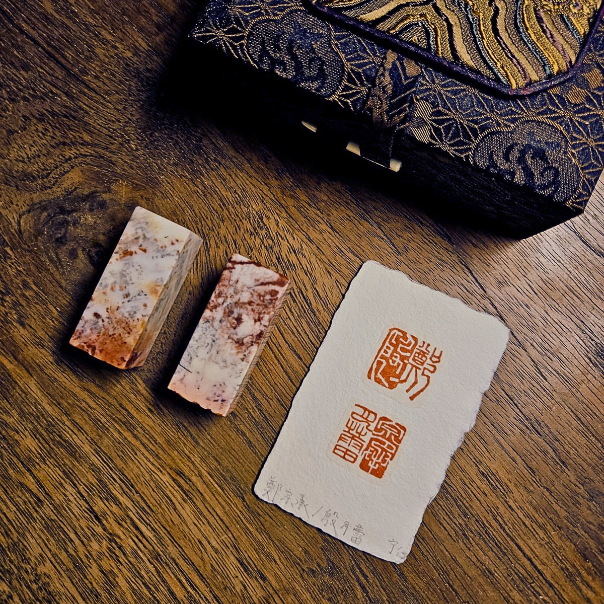 Two hand-carved stone seals with red ink impressions on handmade paper